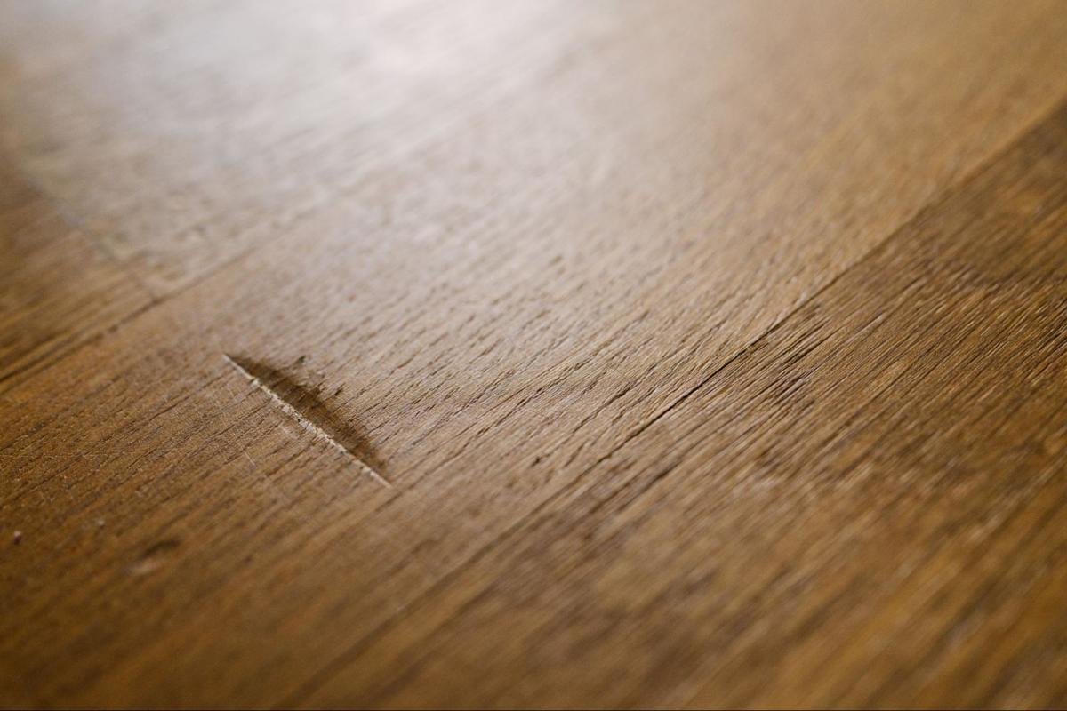 Kleine kras in een houten vloer als voorbeeld van normale slijtage in een huurwoning